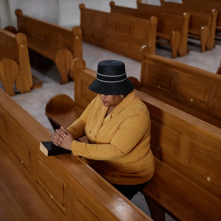 Woman seated on church bench praying.